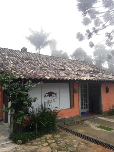 a house with a roof with a tree in the background at Casa no Céu in Petrópolis