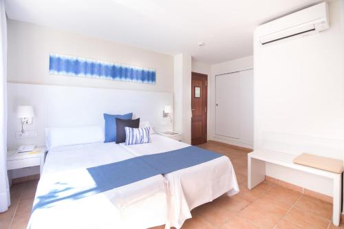 ein Schlafzimmer mit einem großen weißen Bett mit blauer Bettwäsche in der Unterkunft Cabot Pollensa Park Spa in Port de Pollença