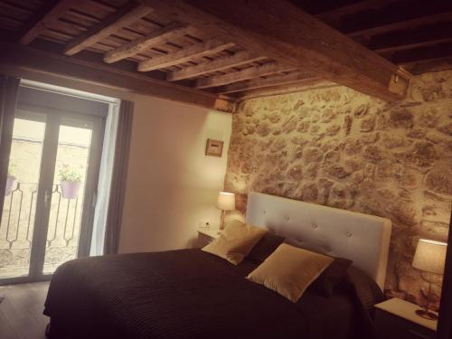 a bedroom with a black bed with a stone wall at Apartamento Zocailla Suite in Gata