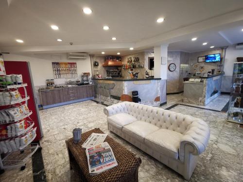 salon z białą kanapą i kuchnią w obiekcie Hotel Clinton w mieście Casoria