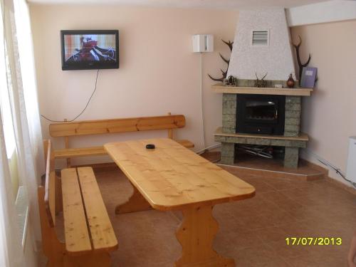 sala de estar con mesa de madera y chimenea en Panayotovi Guest House, en Byala