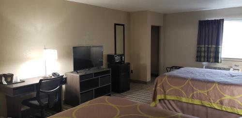 a hotel room with a bed and a desk and a television at Travel Inn Of Sidney Ohio in Sidney