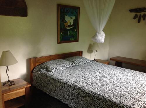 Ce lit se trouve dans une chambre avec deux lampes et une photo. dans l'établissement Piscina Natural on the Sea, à Cahuita