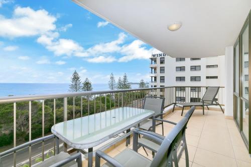 a balcony with a table and chairs and the ocean at Seaview Resort in Mooloolaba