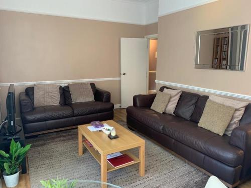 a living room with two leather couches and a coffee table at Be My Guest Liverpool in Liverpool