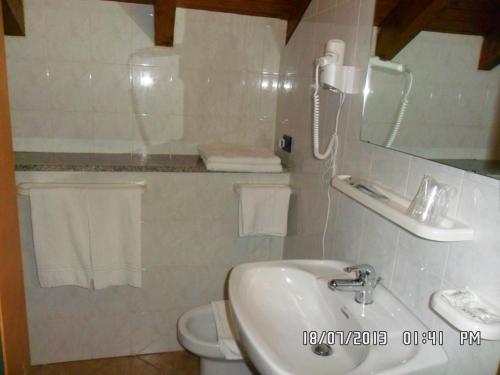 ein Badezimmer mit einem Waschbecken, einem Spiegel und einem WC in der Unterkunft Il Campanile Hotel - La Cantina Del Pittore in Miazzina