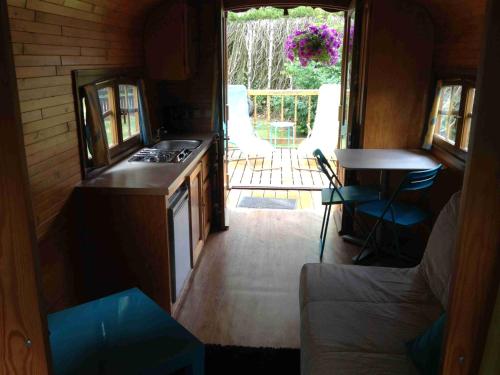 a small kitchen with a stove and a living room at Roulotte du Petit Bois in Theillement