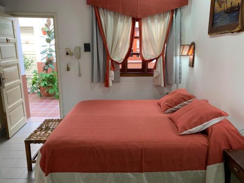 1 dormitorio con 1 cama con edredón rojo y ventana en Departamentos KA.RI.VE en Termas de Río Hondo