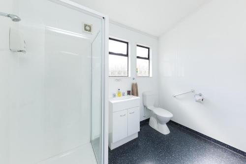 a white bathroom with a toilet and a shower at Manfeild Park Motel in Feilding