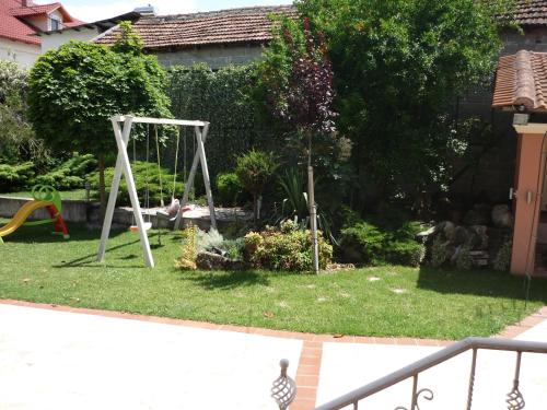 a yard with a swing set in the grass at Erodios Guesthouse in Kato Loutraki