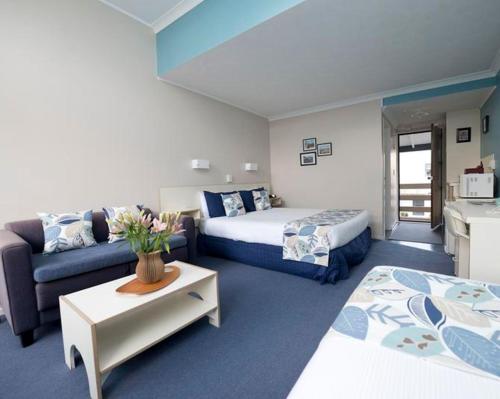 a hotel room with two beds and a couch at Wrights by the Sea Motel in Paraparaumu Beach