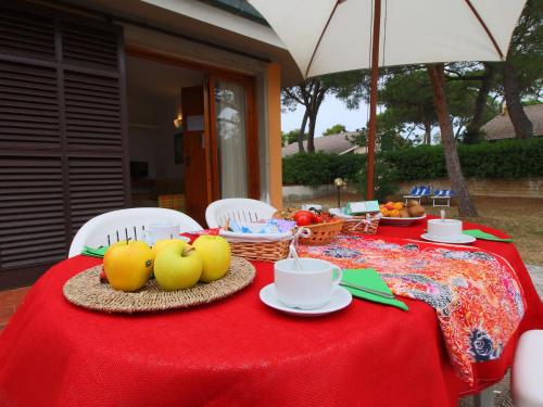Santa LiberataにあるFlat in villa with air condition close to the beachの赤いテーブルクロスと果物を添えたテーブル