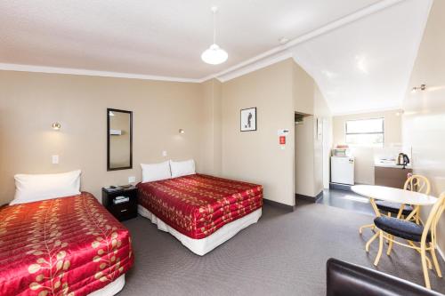 a hotel room with two beds and a table at Manfeild Park Motel in Feilding