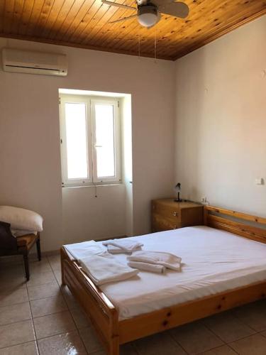 a bedroom with a bed with white sheets and a window at Mythos Suites-Aphrodite apartment in Methoni