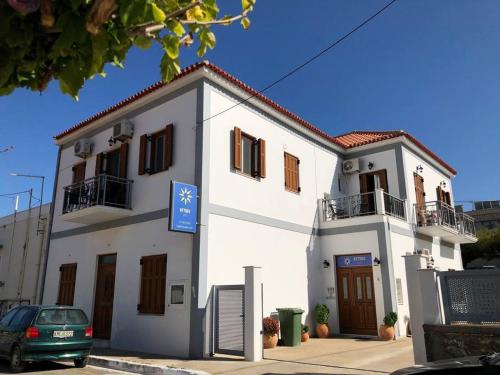 a white building with a car parked in front of it at Mythos Suites-Aphrodite apartment in Methoni