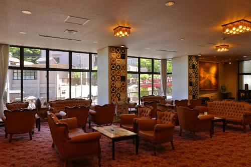 a waiting room with chairs and tables and windows at Arima Gyoen in Kobe