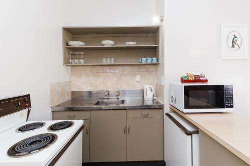 a kitchen with a sink and a microwave at Manfeild Park Motel in Feilding