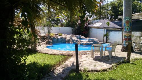 una piscina con una silla y una sombrilla en un patio en El Jardin Colonial, en Calilegua