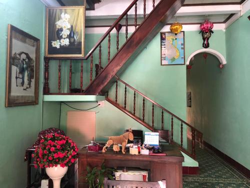 a room with a staircase with a table and flowers at Nha Lan Homestay in Hoi An