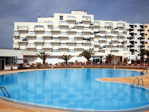 un hôtel avec une grande piscine devant un immeuble dans l'établissement Lagrange Vacances Le Lydia Playa, au Barcarès