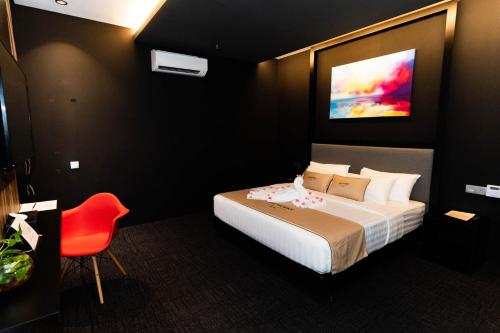 a hotel room with a bed and a red chair at Artworks Hotel Ipoh in Ipoh