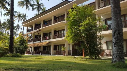 an exterior view of a building with palm trees at Eskala Hotels and Resorts in Ngwesaung