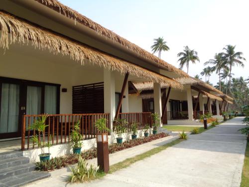a resort with a row of houses with palm trees at Eskala Hotels and Resorts in Ngwesaung