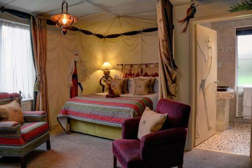 a bedroom with a bed and two chairs at Three Ways House Hotel in Chipping Campden