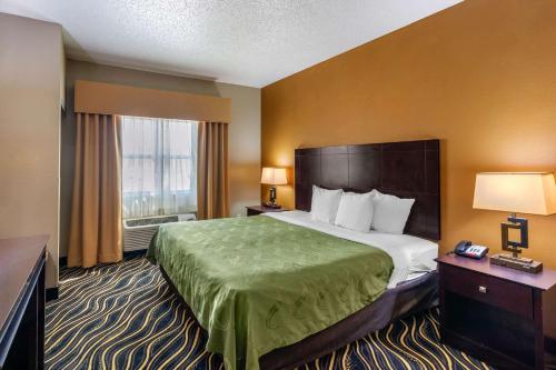 a hotel room with a large bed and a window at Quality Suites Addison-Dallas in Addison