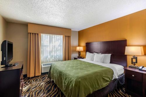 a hotel room with a bed and a television at Quality Suites Addison-Dallas in Addison