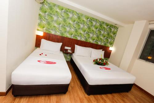 two beds in a hotel room with flowers at My Hotel @ KL Sentral in Kuala Lumpur