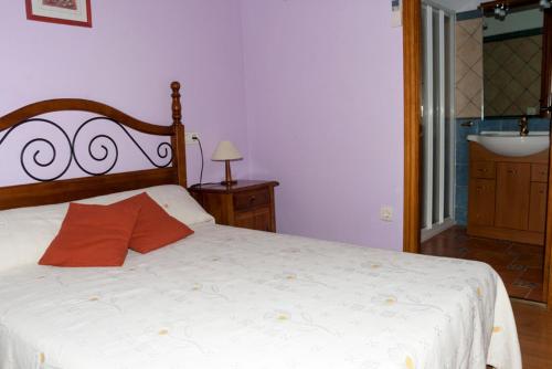 a bedroom with a white bed with a red pillow at Casa Rural Benito in Las Cuevas de Cañart