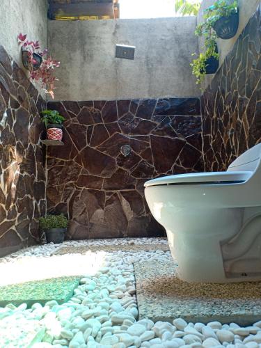 a bathroom with a toilet and a stone wall at Java Turtle Lodge Meru Betiri in Banyuwangi