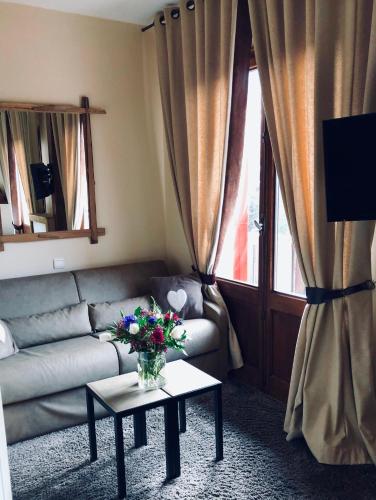 a living room with a couch and a table with flowers at Coeur des Neiges in Saint-Gervais-les-Bains
