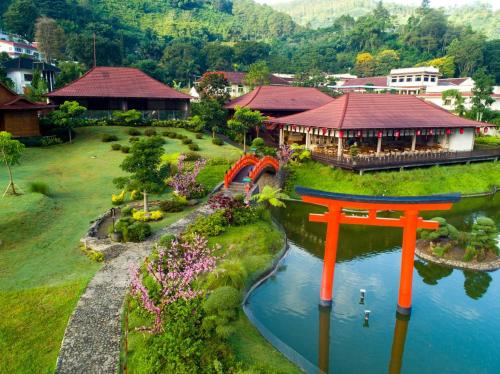un puente naranja sobre un río frente a un edificio en The Onsen Hot Spring Resort, en Batu