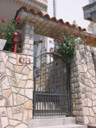a gate in a stone wall with flowers on it at Apartmani Manuela Lopar in Lopar