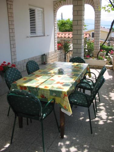 a table with chairs and a quilt on a patio at Apartmani Manuela Lopar in Lopar