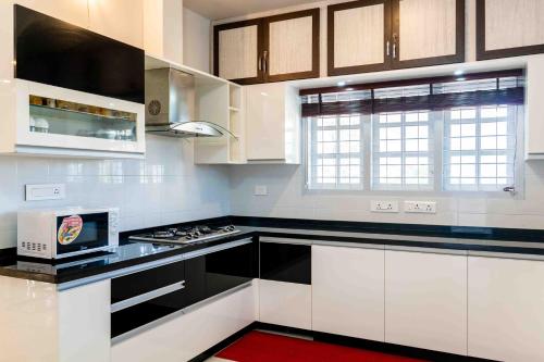 a kitchen with white cabinets and black counter tops at StayVista at Aashirwaad Villa in Coonoor