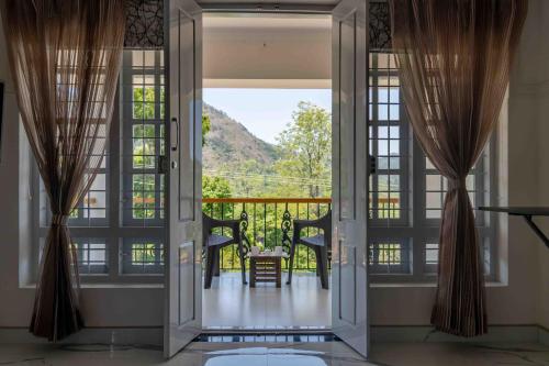 an open door to a balcony with a table and chairs at StayVista at Aashirwaad Villa in Coonoor