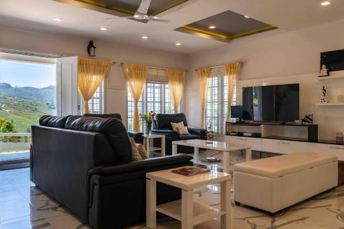 a living room with a black leather couch and a tv at StayVista at Aashirwaad Villa in Coonoor