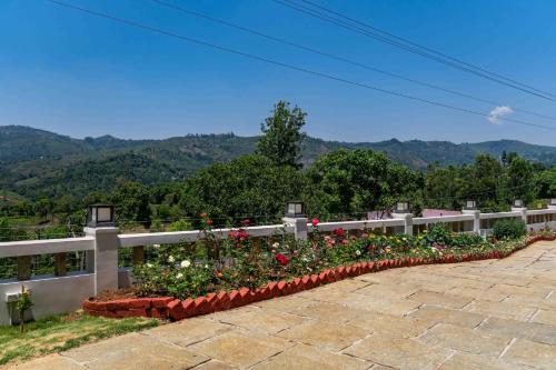 a row of flowers on a fence with mountains in the background at StayVista at Aashirwaad Villa in Coonoor