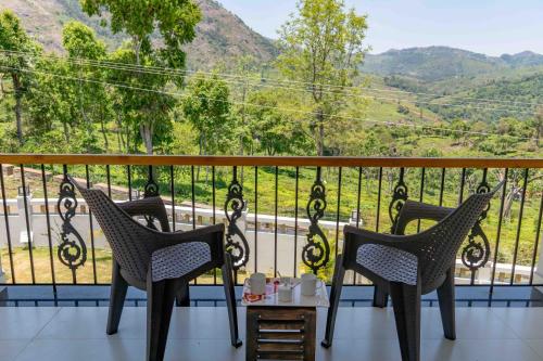 two chairs and a table on a balcony with a view at StayVista at Aashirwaad Villa in Coonoor