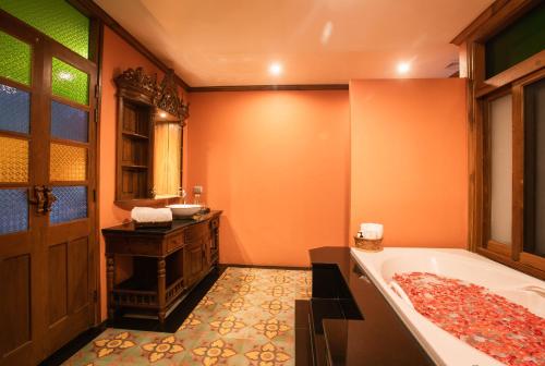 an orange bathroom with a tub and a sink at Pingviman Hotel in Chiang Mai