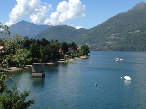 a river with boats in the water and mountains at Casa Nora in Dervio