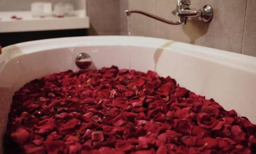 a bath tub filled with red rose petals at Artworks Hotel Ipoh in Ipoh