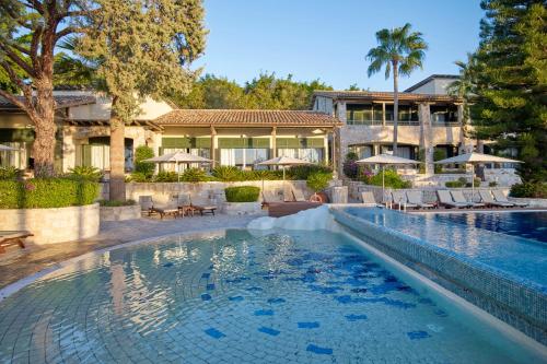 a swimming pool in front of a house at Columbia Beach Resort in Pissouri
