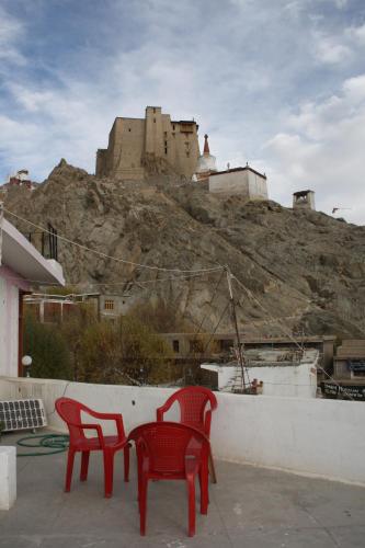 two red chairs and a castle on a hill at Hotel Khan Manzil in Leh