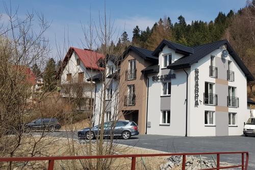 a house with a car parked in a parking lot at Dom Goscinny Skarpa in Krynica Zdrój