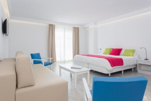 a white bedroom with a bed and a couch at Guya Wave Hotel in Cala Ratjada