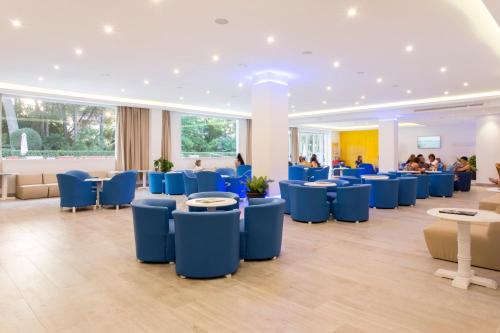 a waiting room with blue chairs and people in the background at Guya Wave Hotel in Cala Ratjada